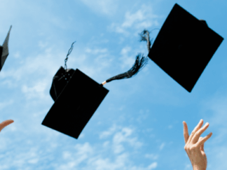 Two hands throwing four graduate caps into the air in front of a blue sky.