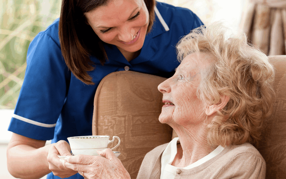 care assistant handing service user a warm drink in a tea cup in a home setting